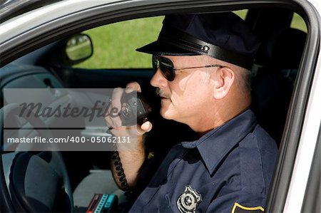 Police officer in squad car talking on his radio.  Closeup view.