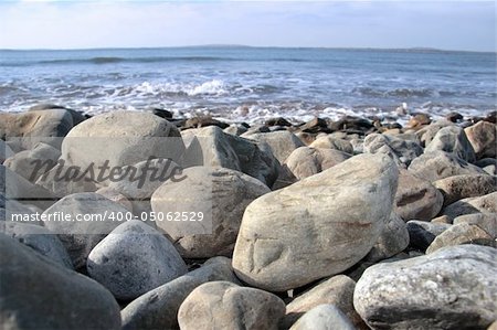 a pebbled beach on a warm day with a calm sea as a background