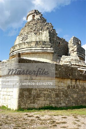 Antique maya observatory over blue sky and green grass