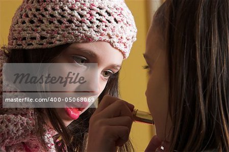 One young girl putting on make-up on another young girl