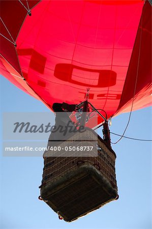 A man is standing in his hot air balloon waving with his hand.