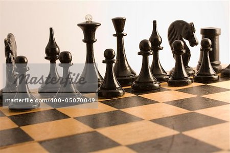 Black chess are placed on a wooden chess board for the beginning games