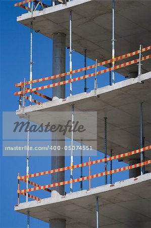 Part of unfinished building with caution marks and concrete walls