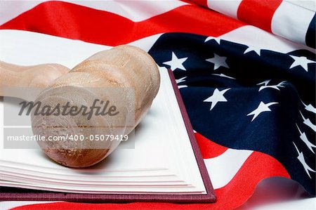 An open law book and a judges gavel on an American flag.