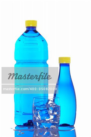 Two bottles and glass of mineral water with droplets reflected on white background