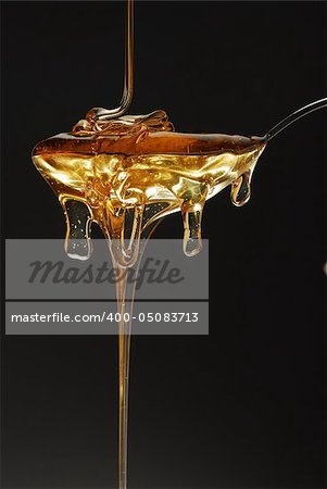 Golden honey spilling over black background stock photo
