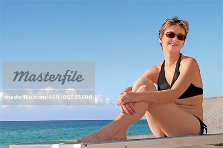 A happy mature woman relaxing on a beach by the ocean