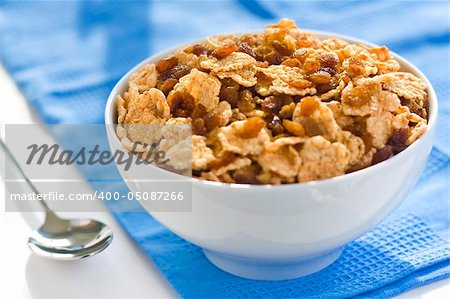 bowl of cereal with raisins, milk and orange juice