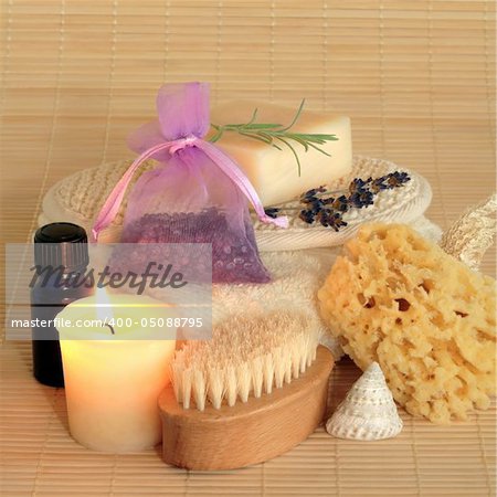 Natural beauty products, against bamboo matting background, lit by a candle.