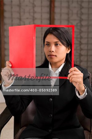 A young businesswoman holding a magazine (look like she reads it) where her face is on cover page.