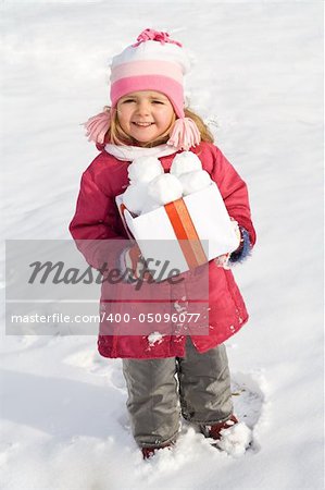 Glückliches kleines Mädchen mit einem Kasten Schneebälle im winter