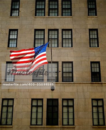 An American flag waving on the facade of a building.