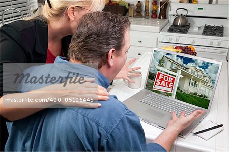 Couple In Kitchen Using Laptop to Research Real Estate. Screen can be easily used for your own message or picture. Picture on screen is my copyright as well.
