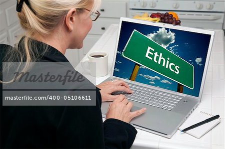 Woman In Kitchen Using Laptop with Ethics Road Sign on Screen. Screen can be easily used for your own message or picture. Picture on screen is my copyright as well.