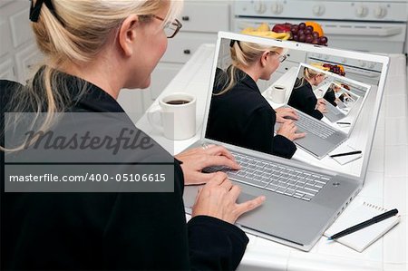Woman In Kitchen Using Laptop. Screen can be easily used for your own message or picture. Picture on screen is my copyright as well.
