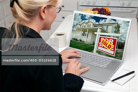 Woman In Kitchen Using Laptop to Research Real Estate. Screen can be easily used for your own message or picture. Picture on screen is my copyright as well.