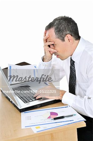 Stressed businessman sitting at his desk isolated on white background