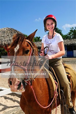 Young girl riding brown horse wearing helmet