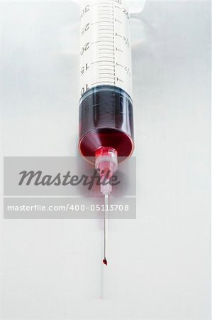 Large syringe filled with red lquid on stainless steel table