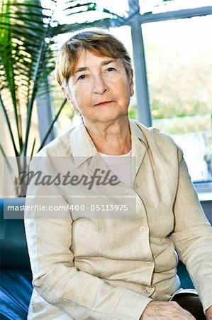 Sad elderly woman sitting on a couch indoors