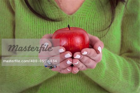 young woman holding healthy red apple in the hands - focus on the apple