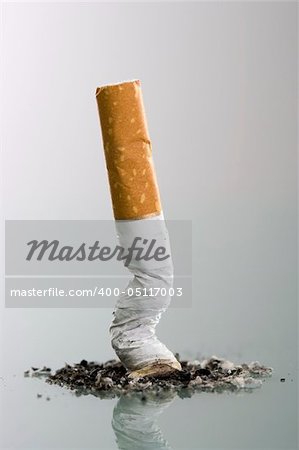 Cigarett butt end crushed into ashtray - grey background