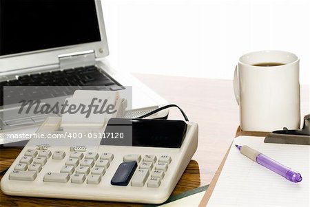 An office desk with a cup of coffee, a calculator and a laptop, isolated against a white background