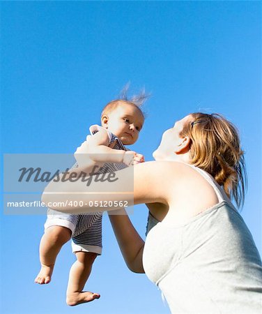 Mother throwing baby against the blue sky