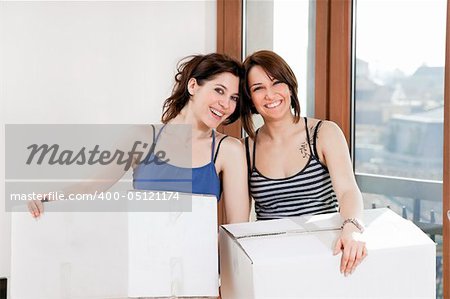 two young women holding cardboard boxes and looking at camera