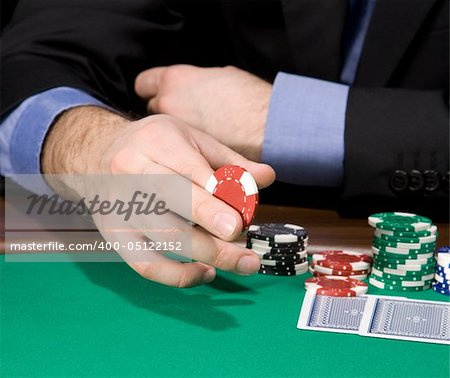 Hand of man holding casino chip over green felt