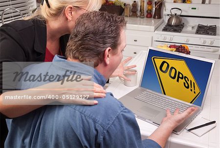 Couple In Kitchen Using Laptop with Yellow Oops Road Sign on the Screen.