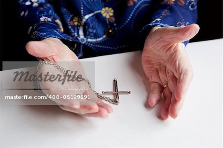 A pair of old hands and a cross - shallow depth of field with focus on the cross