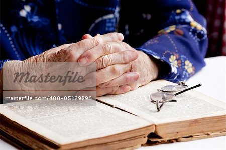 An old pair of hands in prayer on a book