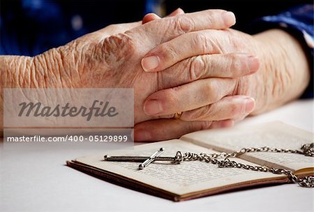 Old female hands with a cross and book