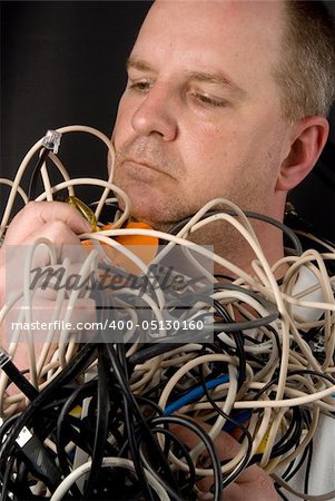 A man tangled up in wires and cables.