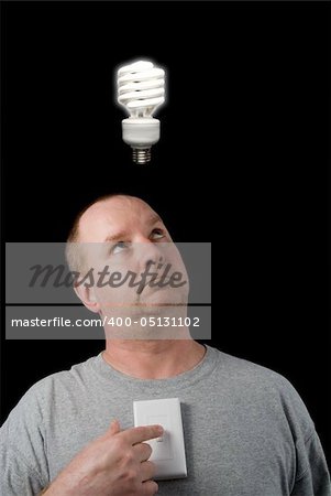A man looking at a lighted lightbulb over his head.