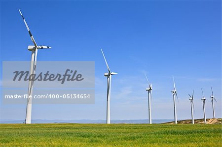 Wind turbines farm in green field over cloudy sky