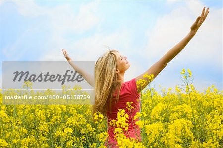 happy blond girl with open arms in a big hug to the sky in a yellow field