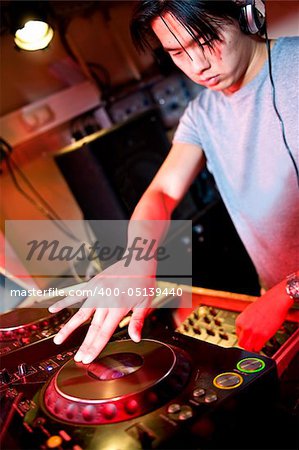 Disc jockey at work behind a turn table in a discotheque