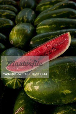 Image of a slice of watermelon on a bed of whole watermelons