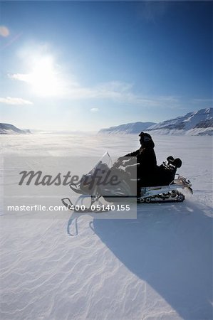 A snowmobile on frozen ice on a barren winter landscape