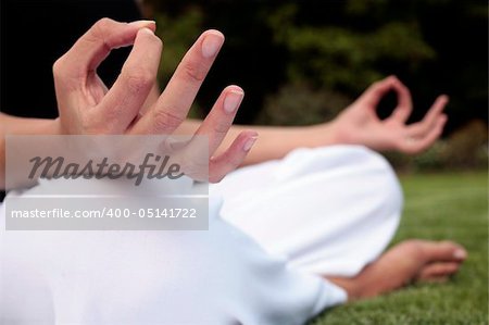 Woman sitting down meditating on a lawn