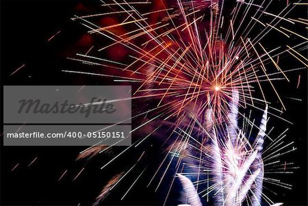 Fireworks exploding in the dark of the evening sky.