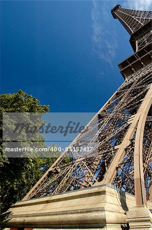 Unusual perspective of the Eiffel Tower, taken with a wide angle lens, with a blue sky background