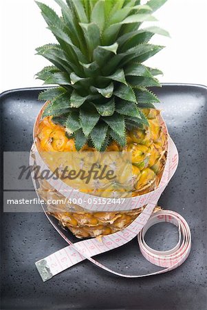 pineapple on a black plate with tape meter isolated on white background