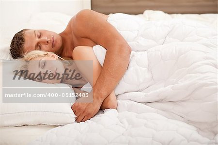 Young couple sleeping and hugging on bed