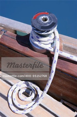 Marine rope and winch over wooden deck and blue summer sea
