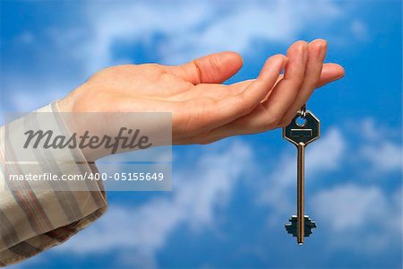 Hand holding a key over sky and clouds backgound