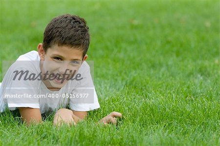 a boy is smiling on the green grass