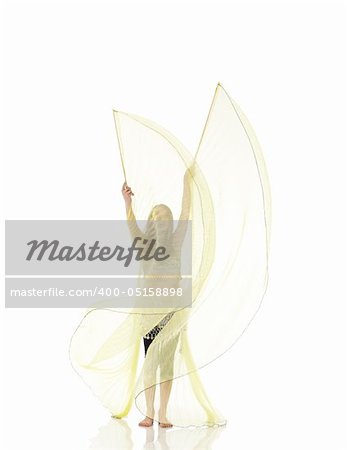 Young Caucasian belly dancing girl in beautiful decorated clothes on white background and reflective floor. Not isolated